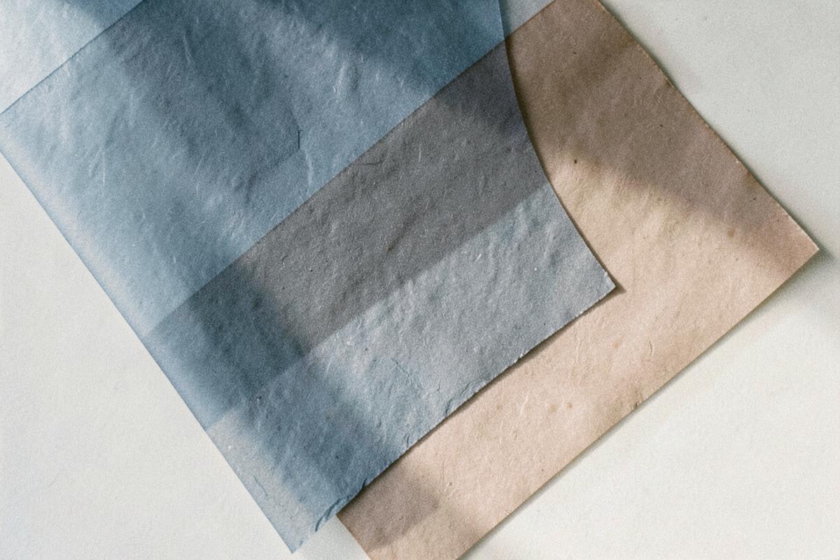 Overlapping sheets of slate blue and taupe paper in soft light